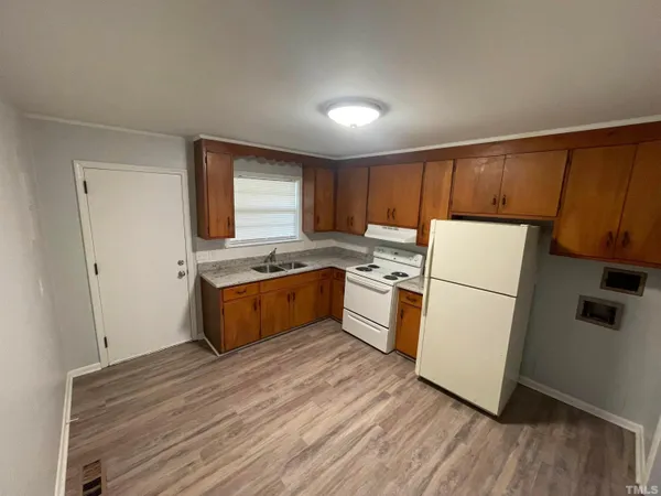 a kitchen with a refrigerator a sink and wooden floor