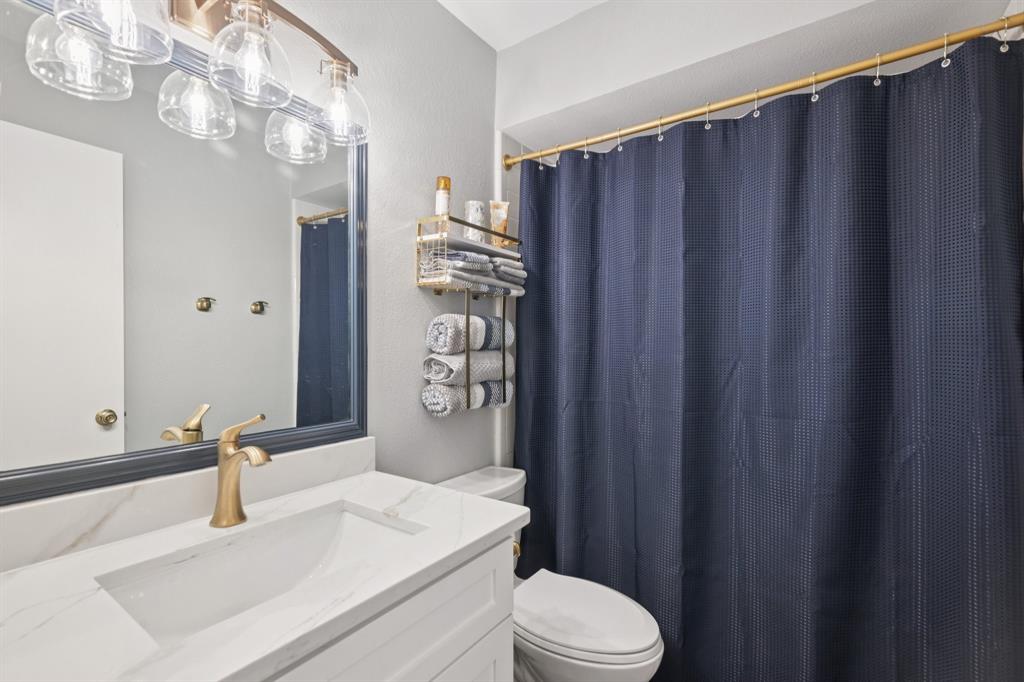 209 Cimarron Trail, Unit 6 Irving, TX 75063 - Photo 14 of 39 a bathroom with a sink a toilet a mirror and shower curtain