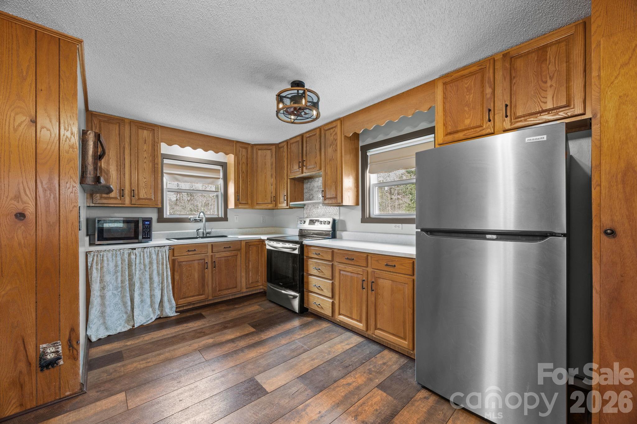 1169 Rickman Creek Road Franklin, NC 28734 - Photo 5 of 43 a kitchen with stainless steel appliances granite countertop a refrigerator a sink dishwasher a stove with wooden cabinets and floor