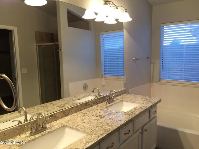 an empty room with wooden floor chandelier fan and windows