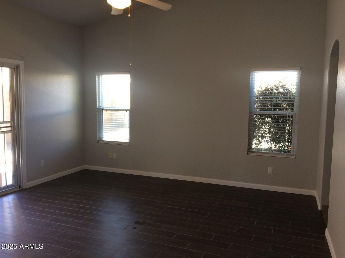 2240 East Aire Libre Avenue Phoenix, AZ 85022 - Photo 13 of 18 an empty room with wooden floor chandelier fan and windows