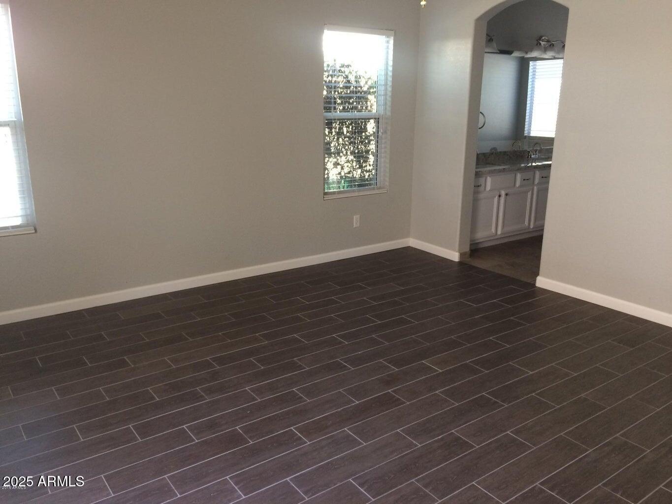 2240 East Aire Libre Avenue Phoenix, AZ 85022 - Photo 7 of 18 an empty room with wooden floor and windows
