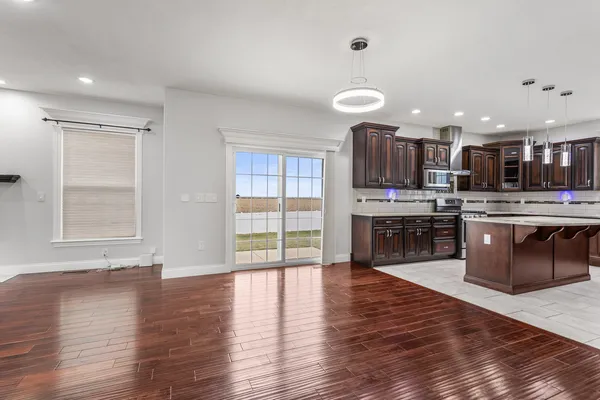 a open kitchen with stainless steel appliances granite countertop a stove top oven a sink and dishwasher with wooden floor