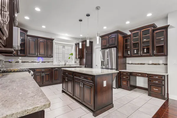 a kitchen with stainless steel appliances granite countertop a stove top oven a sink dishwasher a refrigerator and a oven with wooden cabinets