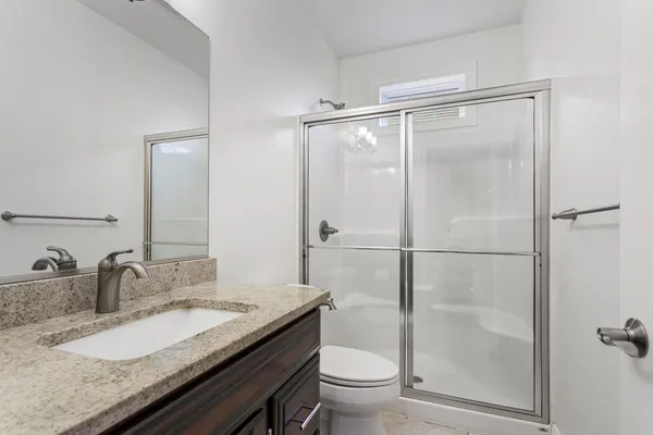 a bathroom with a granite countertop sink toilet and shower