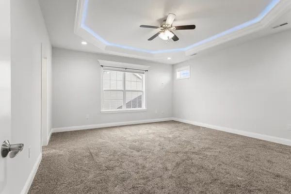 an empty room with windows and ceiling fan