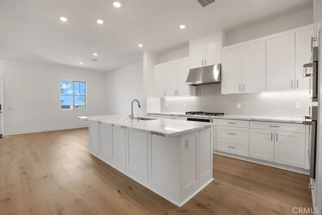 a kitchen with stainless steel appliances granite countertop a sink stove and cabinets with wooden floor