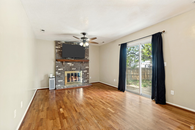 843 Deer Flat Road Tooele, UT 84074 - Photo 11 of 27 Living area featuring wood-finish flooring, a brick-front fireplace with a wood mantel, and an overhead ceiling fan