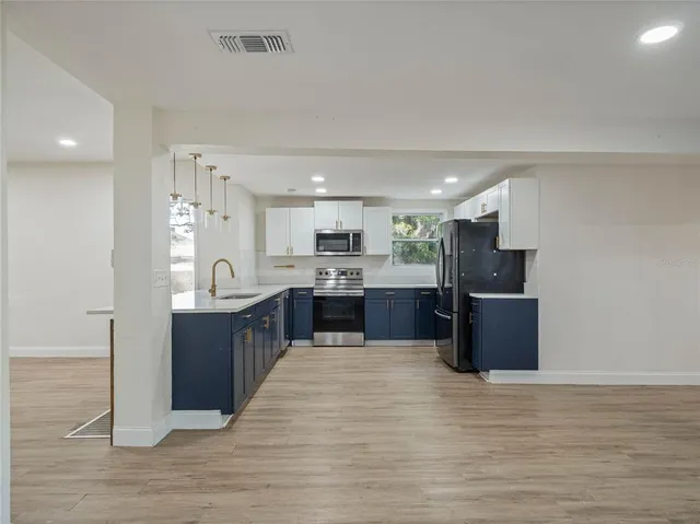 a large kitchen with stainless steel appliances kitchen island granite countertop a refrigerator and a stove top oven