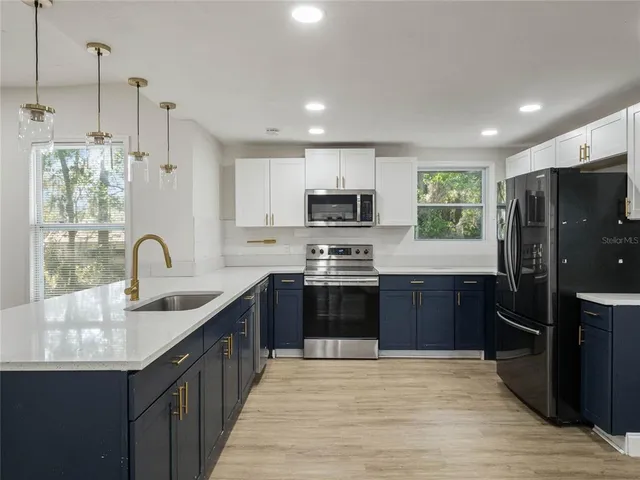 a kitchen with stainless steel appliances granite countertop a sink refrigerator and cabinets