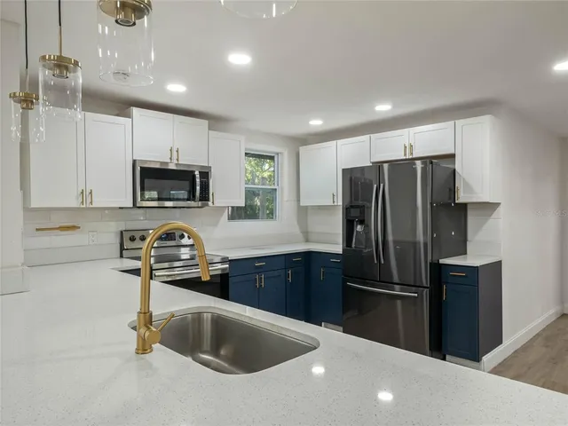 a kitchen with stainless steel appliances a refrigerator a sink a stove a microwave and cabinets