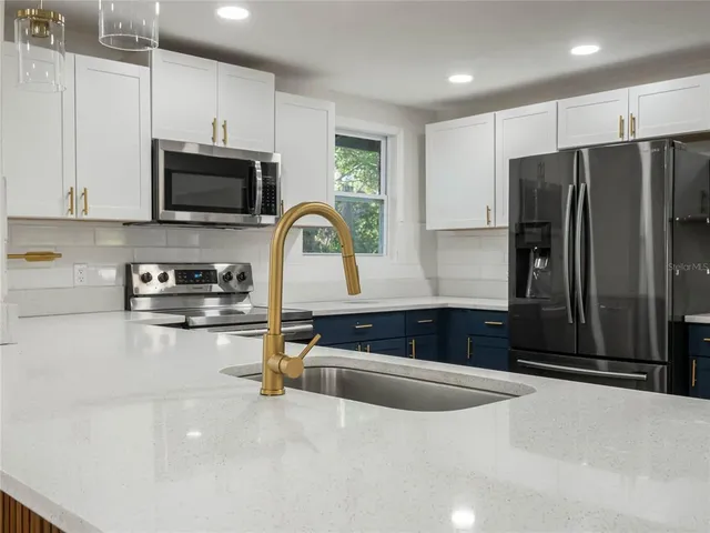 a kitchen with granite countertop a refrigerator and a stove top oven