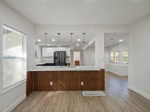 a open kitchen with kitchen island a sink dishwasher a stove and a refrigerator with wooden floor