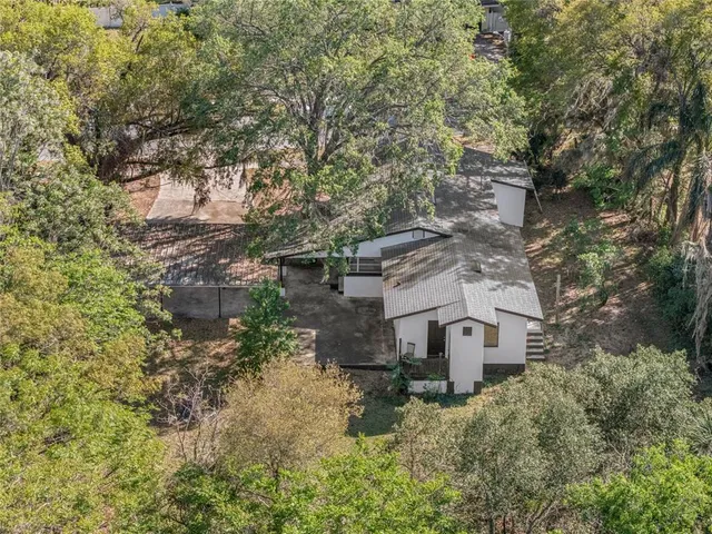 an aerial view of a house with large trees