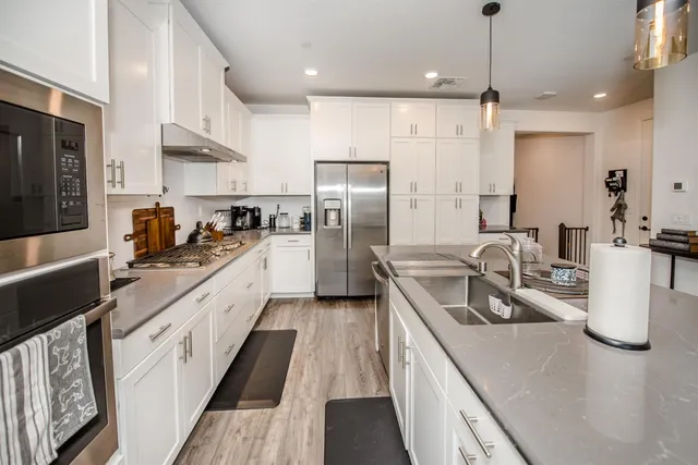 a kitchen with stainless steel appliances granite countertop a sink a stove and a wooden floors
