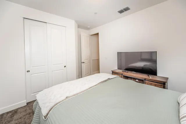 a bedroom with a bed a dresser with wooden floor