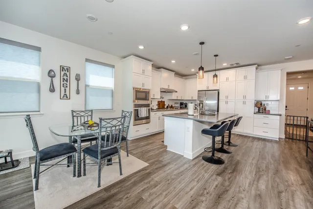 a kitchen with stainless steel appliances granite countertop a sink a stove and a wooden floor