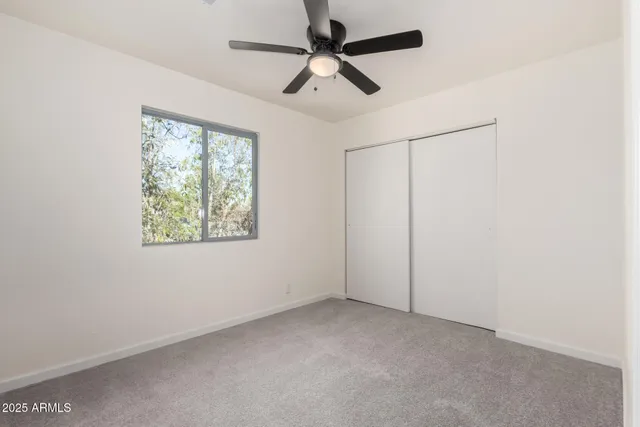 an empty room with a window and a fan