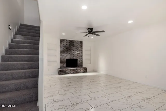 a view of an empty room with stairs and a fireplace
