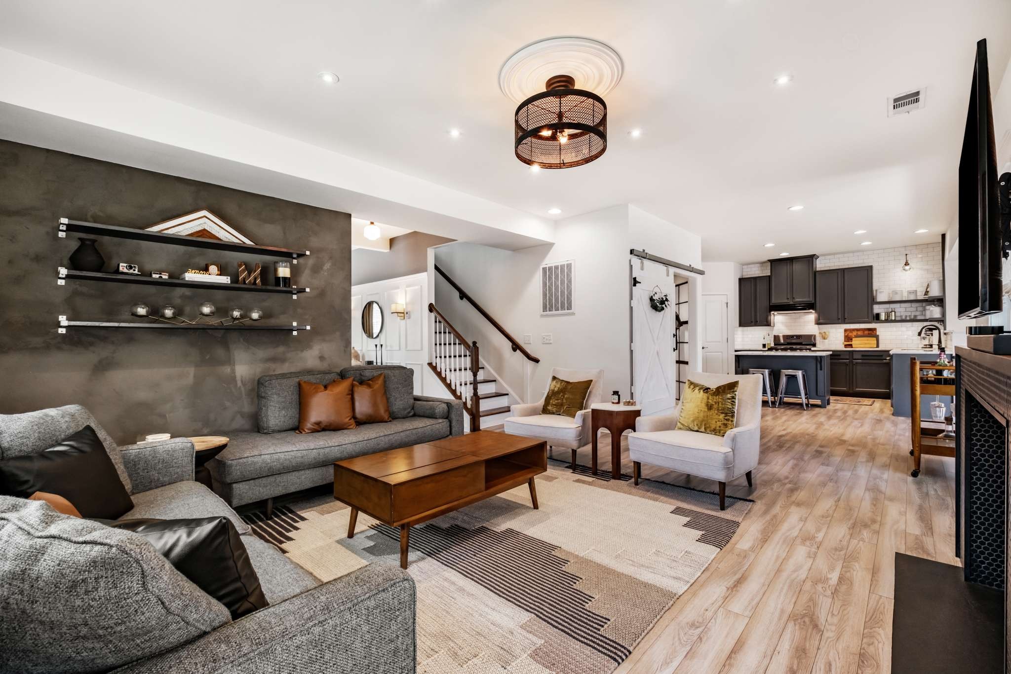 a living room with furniture kitchen view and a chandelier