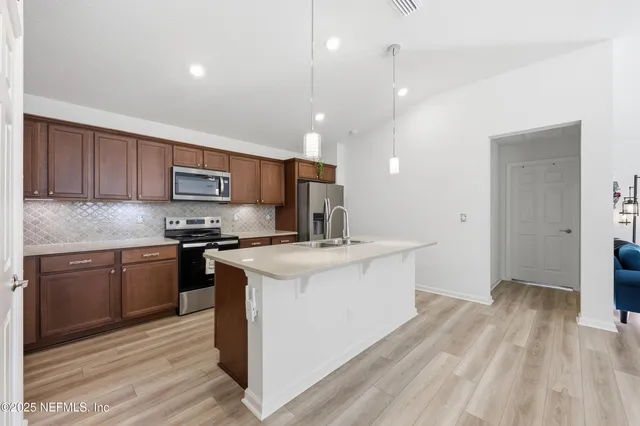 a kitchen with a sink wooden floor and stainless steel appliances