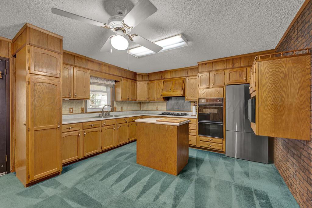 5025 South Crockett Street Amarillo, TX 79110 - Photo 4 of 30 a kitchen with stainless steel appliances granite countertop a refrigerator a sink dishwasher a stove with wooden cabinets and floor