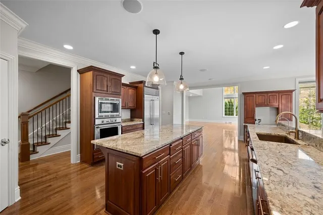 a kitchen with stainless steel appliances granite countertop a sink a stove and a wooden floors