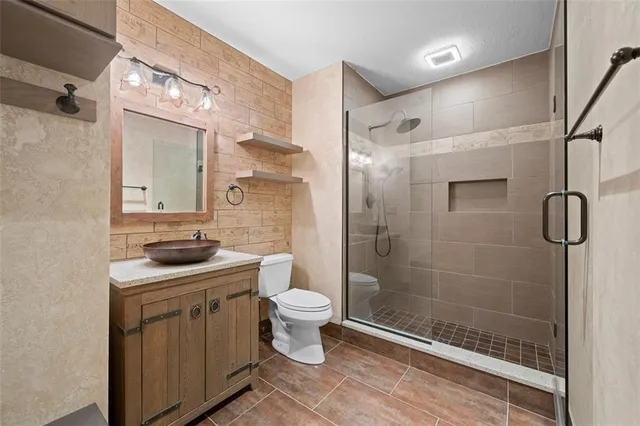 a bathroom with a granite countertop sink a toilet and shower