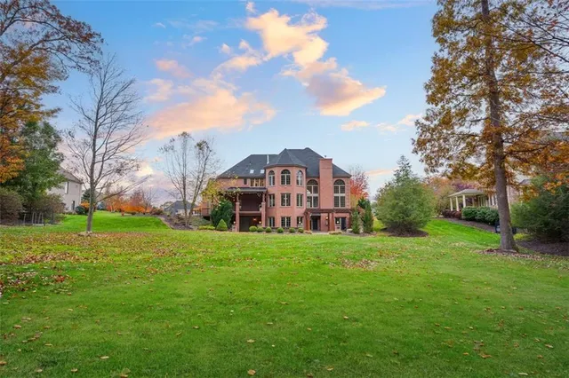 a view of a big house with a big yard and large trees