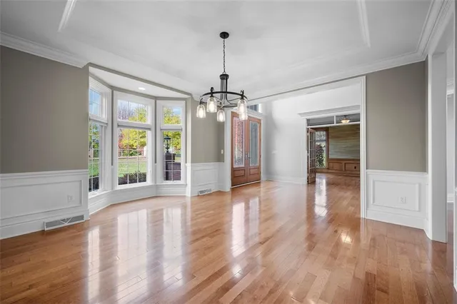 a view of a room with wooden floor chandelier and windows