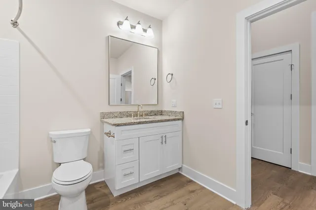 a bathroom with a granite countertop toilet sink and mirror
