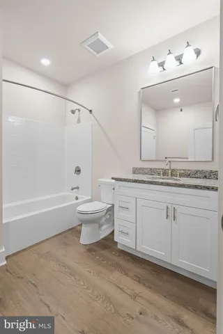 a spacious bathroom with a granite countertop sink a toilet and bathtub