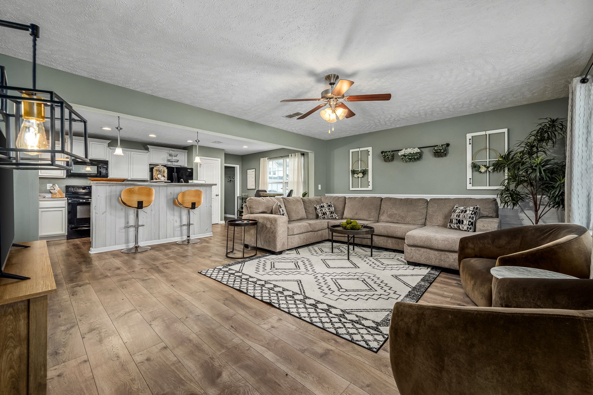 a living room with furniture kitchen view and a chandelier