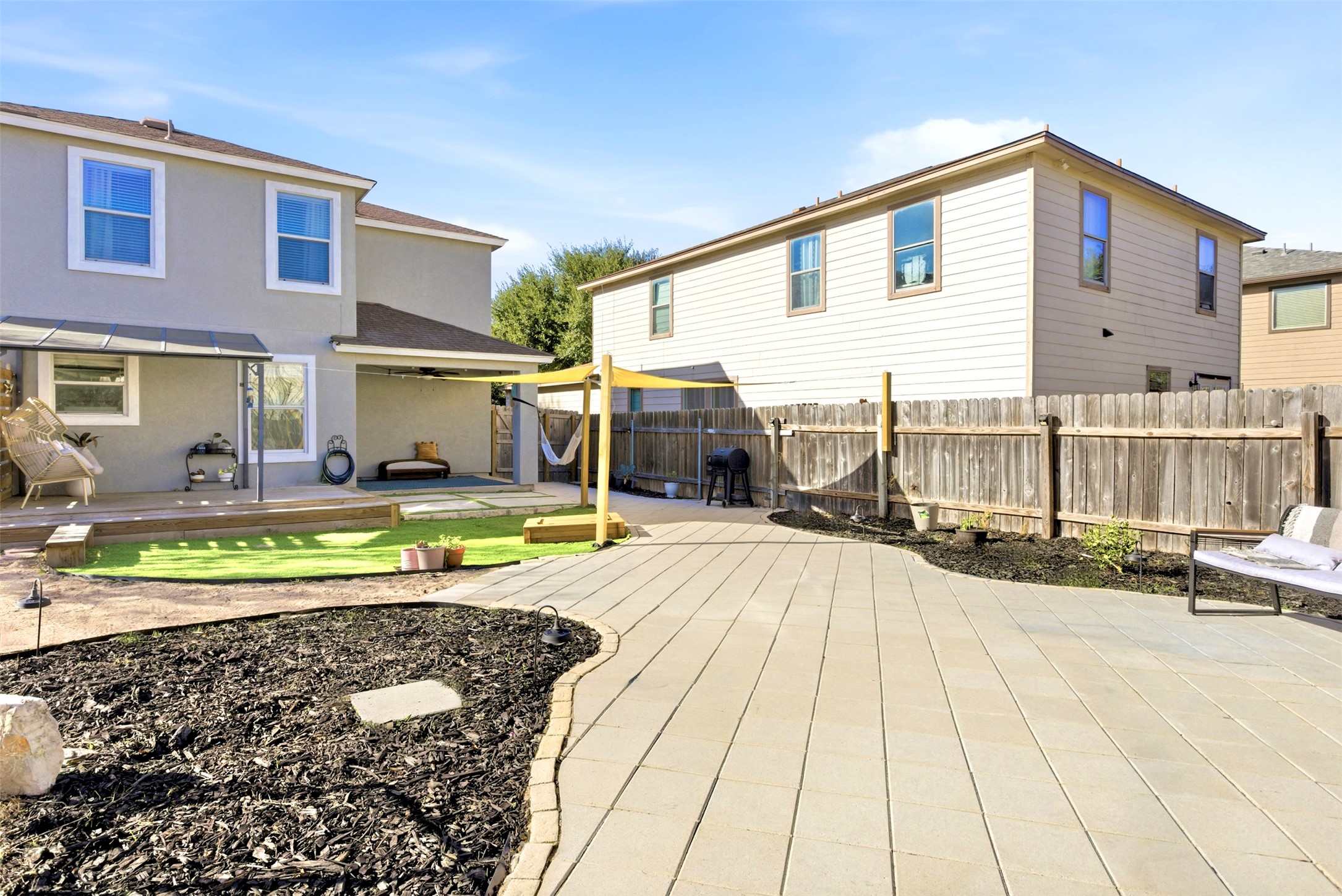 75 Jan Lane Georgetown, TX 78626 - Photo 30 of 32 Rear exterior showcasing covered patio areas, deck space, shade sail, and turf yard—ideal for outdoor living and entertaining.