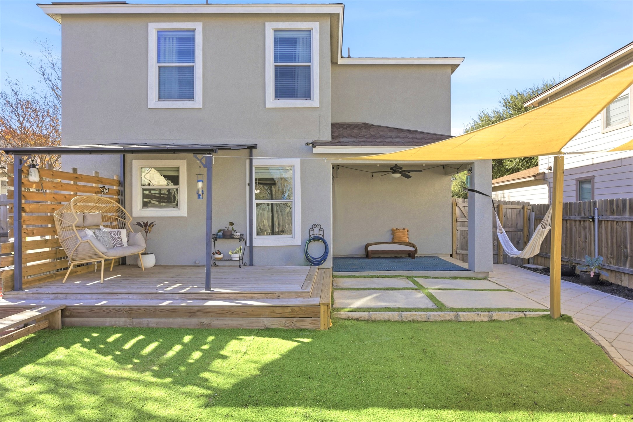 75 Jan Lane Georgetown, TX 78626 - Photo 3 of 32 Rear exterior showcasing covered patio areas, deck space, shade sail, and turf yard—ideal for outdoor living and entertaining.