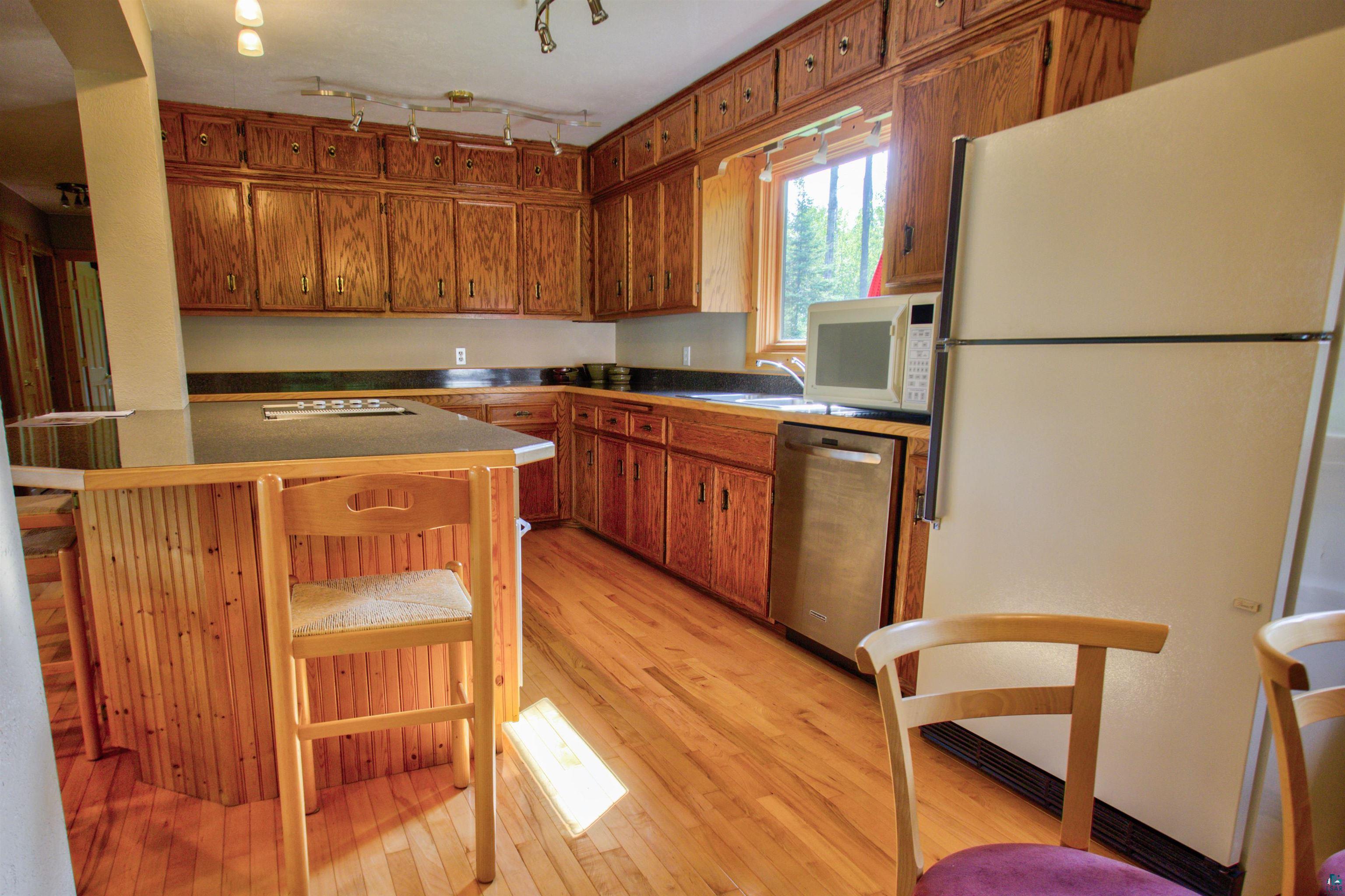 12351 Endless Waters Road Ely, MN 55731 - Photo 23 of 48 Kitchen featuring white appliances, light wood finished floors, brown cabinets, and dark countertops