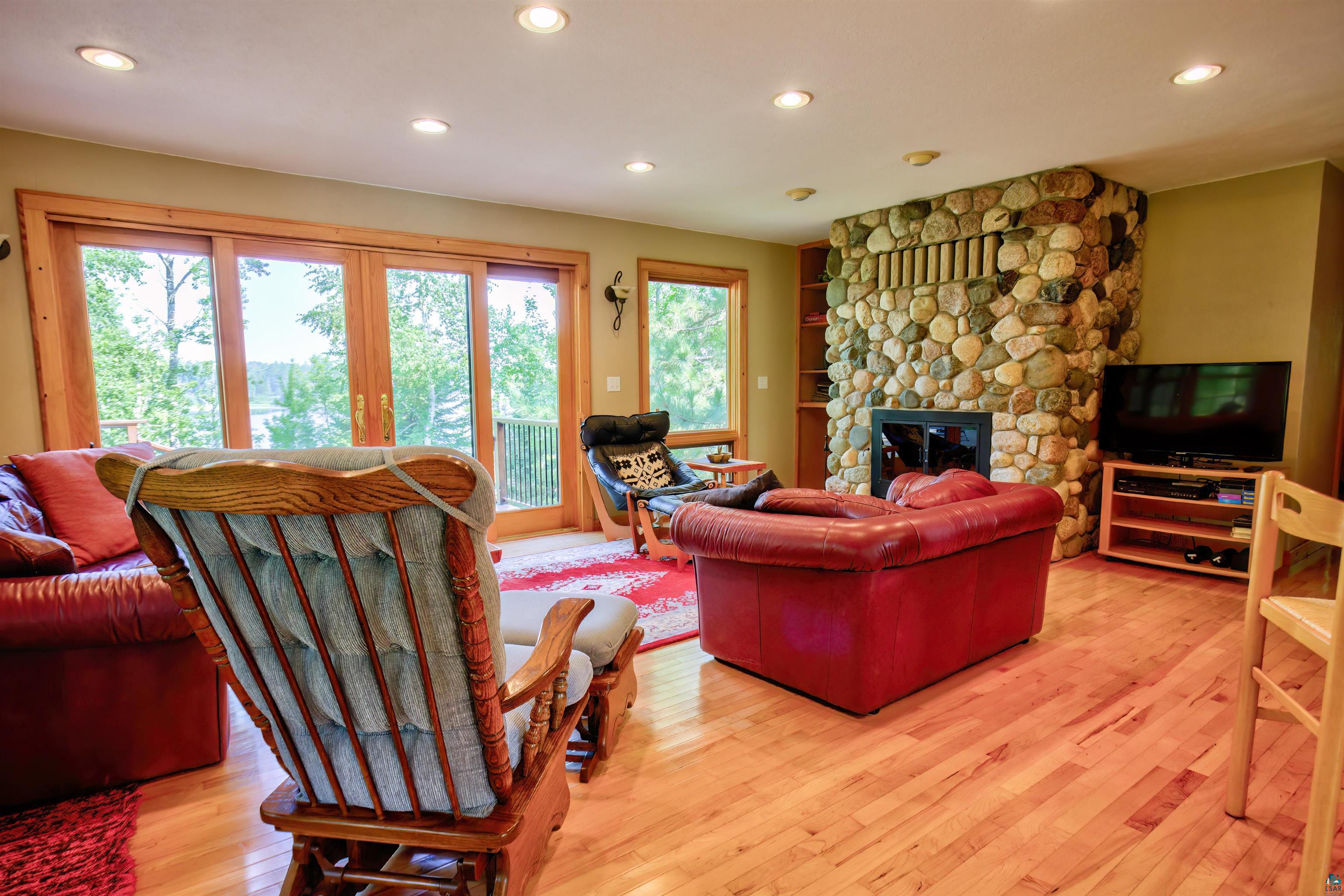 12351 Endless Waters Road Ely, MN 55731 - Photo 31 of 48 Living room with light wood-style floors, recessed lighting, a stone fireplace, and french doors