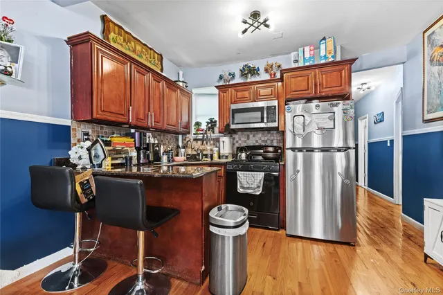 a kitchen with granite countertop a refrigerator a stove and a wooden floors