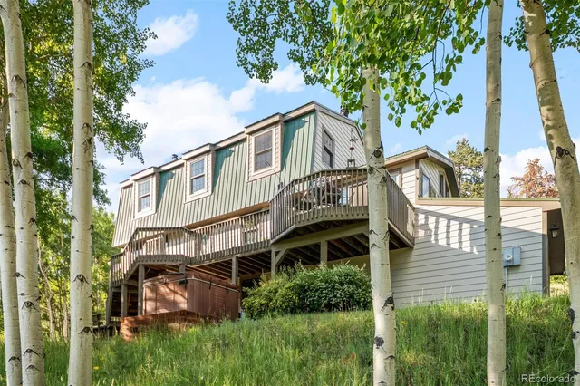 a view of a house with a small yard plants and large trees