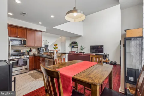 a kitchen with stainless steel appliances wooden floor dining table and chairs