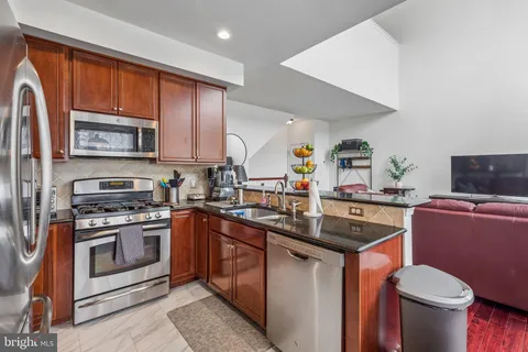 a kitchen with stainless steel appliances granite countertop a stove top oven a sink dishwasher a dining table and chairs with wooden floor