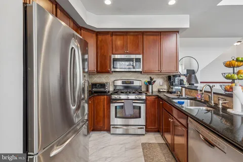 a kitchen with stainless steel appliances granite countertop a refrigerator stove and sink