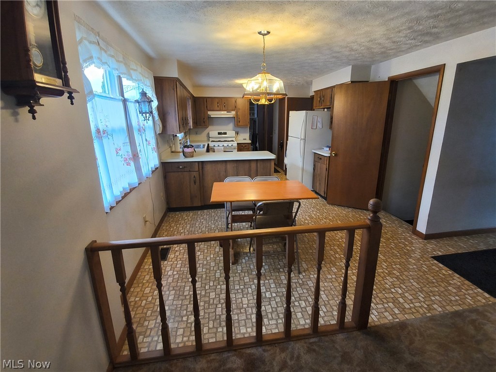 2672 Crackel Road Aurora, OH 44202 - Photo 25 of 38 Kitchen with light countertops, wood finish cabinets, white appliances, suspended lighting, and a textured ceiling