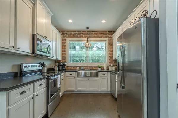 a kitchen with stainless steel appliances granite countertop a sink a stove and a refrigerator