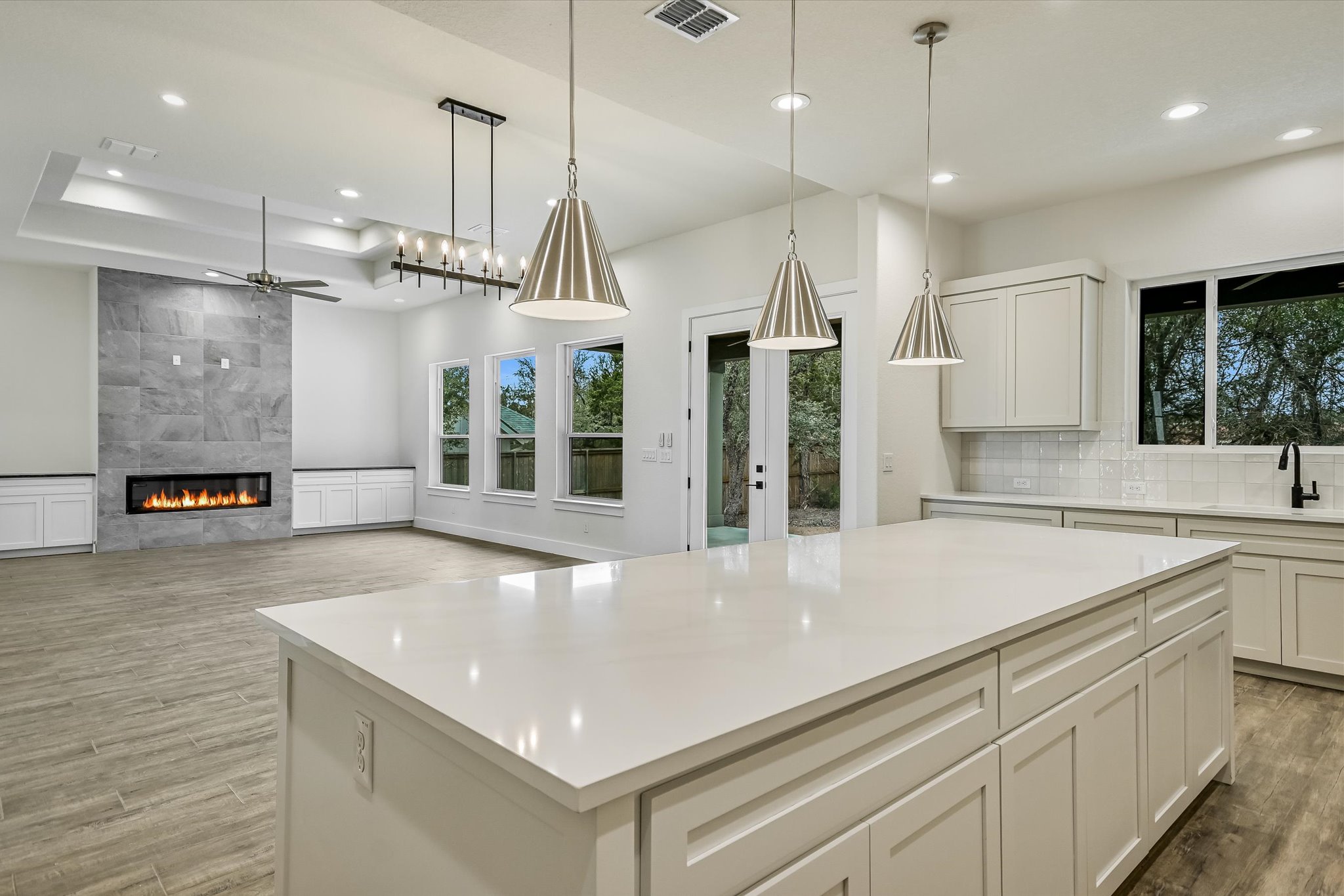32 Peace Pipe Wimberley, TX 78676 - Photo 9 of 20 Kitchen featuring a fireplace, light wood-style floors, white cabinetry, a ceiling fan, and a tray ceiling