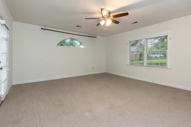 an empty room with windows and fan
