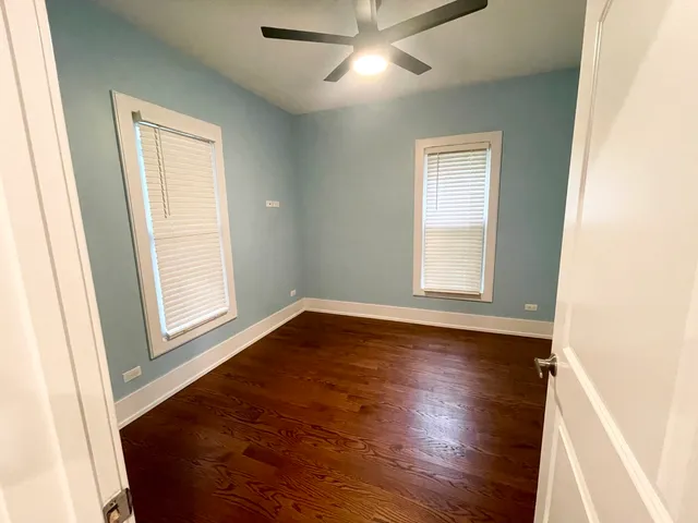 a view of empty room with wooden floor and fan