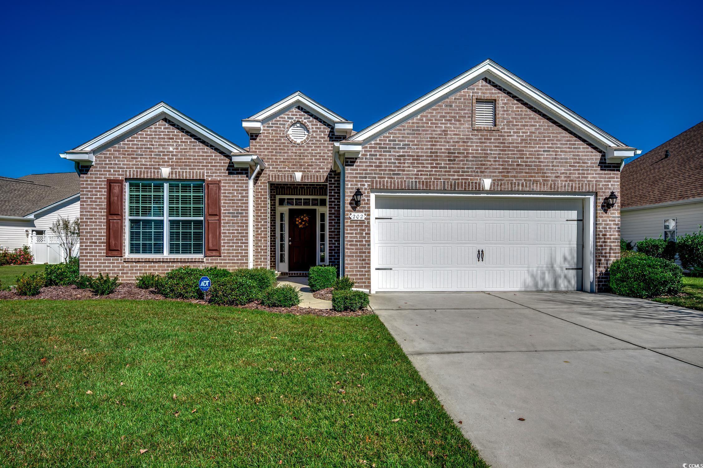 Ranch-style house featuring driveway, brick siding, a garage, and a front yard