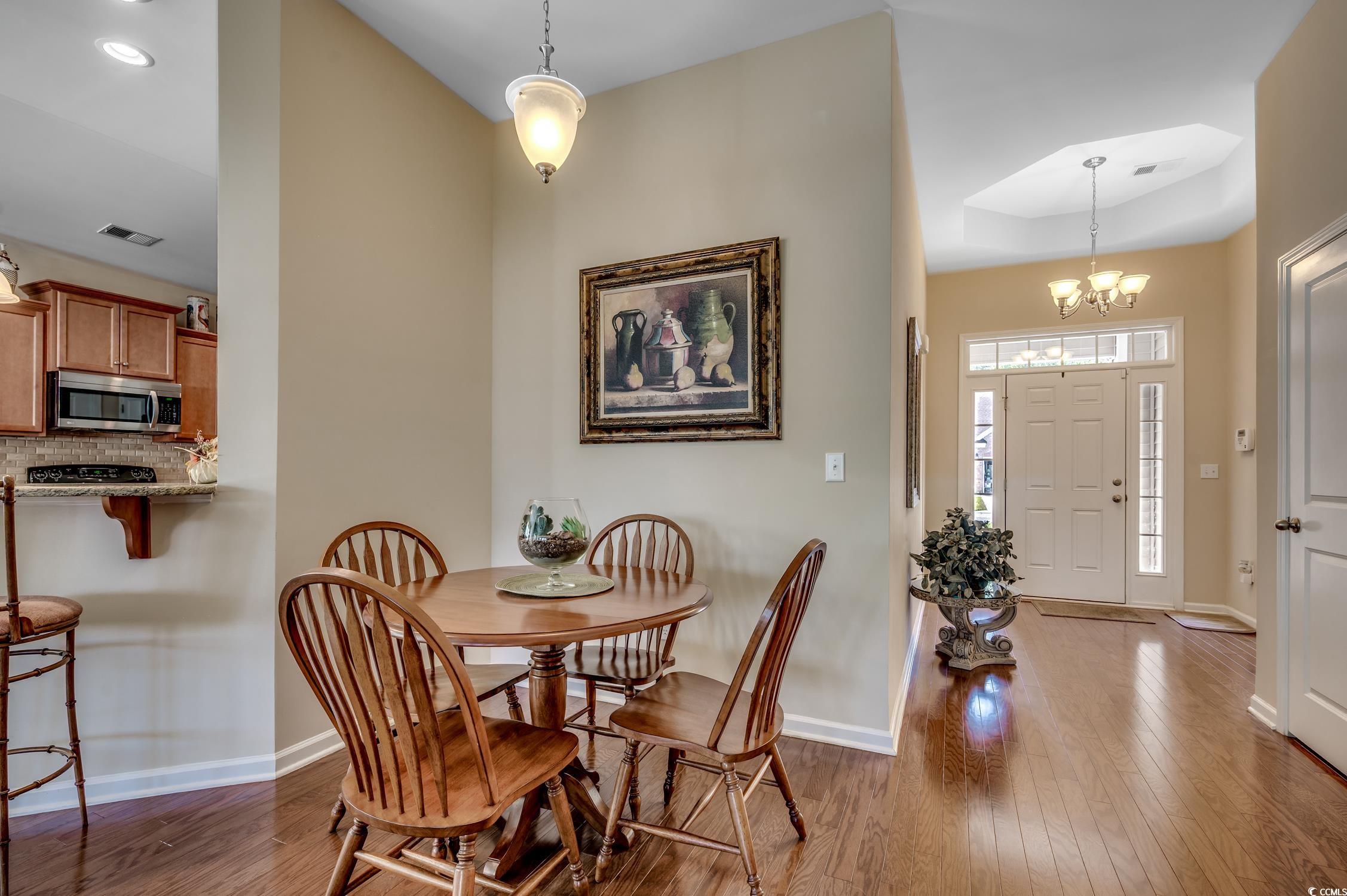 202 Fox Den Drive Murrells Inlet, SC 29576 - Photo 13 of 35 Dining area featuring dark wood-style flooring, a chandelier, and a raised ceiling