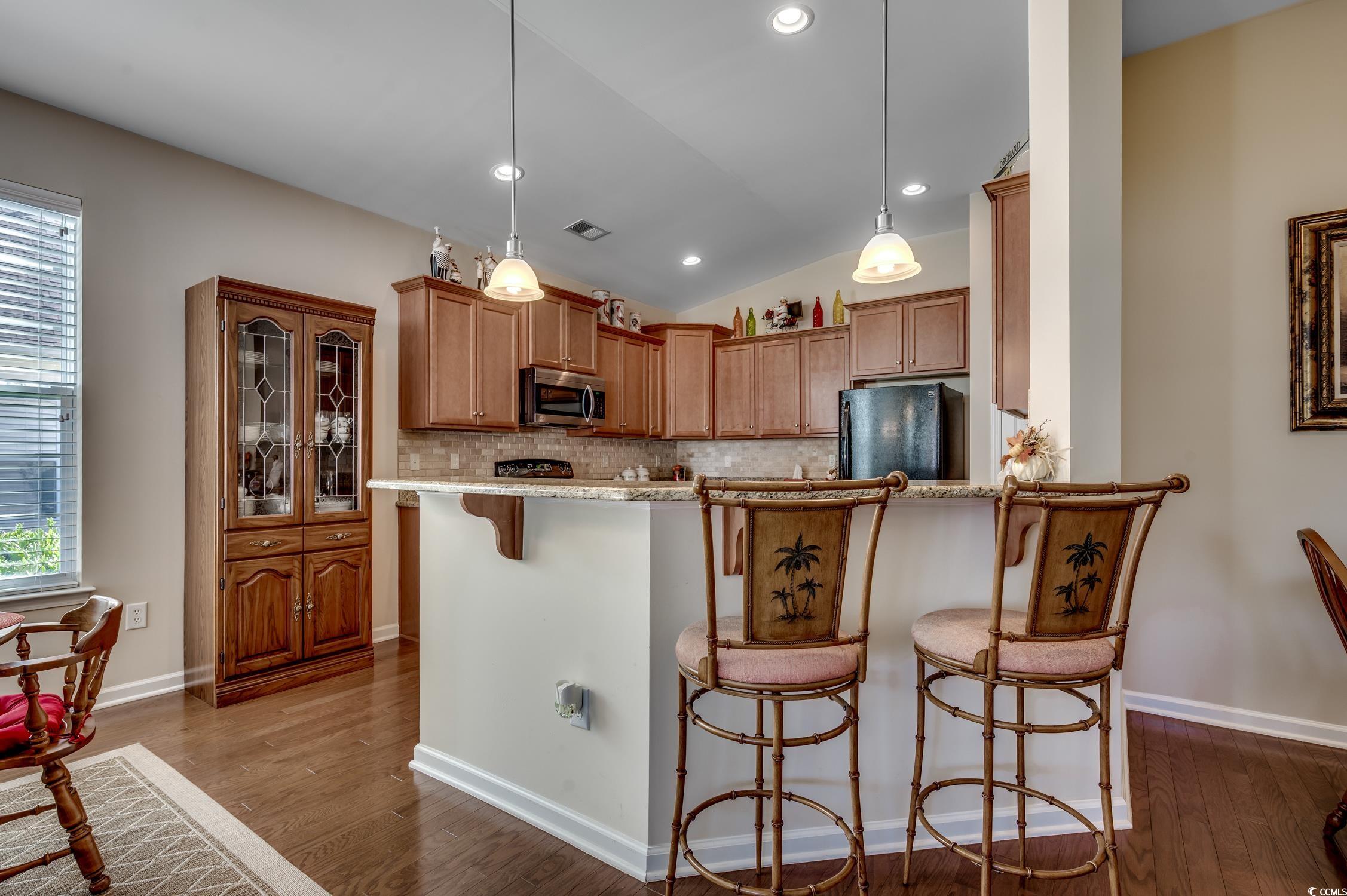 202 Fox Den Drive Murrells Inlet, SC 29576 - Photo 15 of 35 Kitchen featuring a breakfast bar area, vaulted ceiling, backsplash, pendant lighting, and dark wood-style flooring